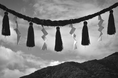 Low angle view of artwork hanging on rope by mountain against sky