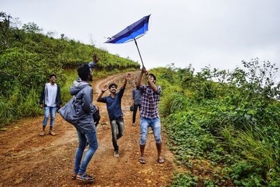 Friends looking at damaged umbrella while hiking on mountain during monsoon