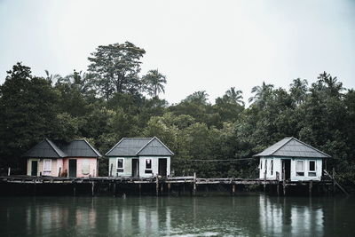 Stilt houses at lake against clear sky