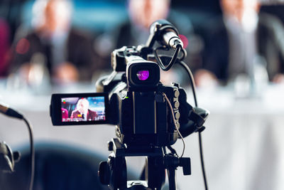 Professional digital camera recording presentation of a blurred speaker wearing suit
