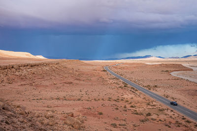 Scenic view of highway through desert against dramatic sky in summer