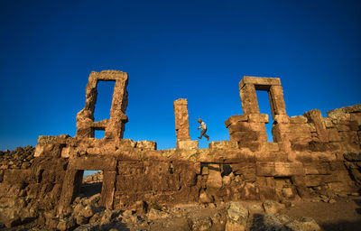 Low angle view of old ruins against clear blue sky