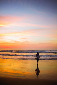 Silhouette man standing on beach against sky during sunset