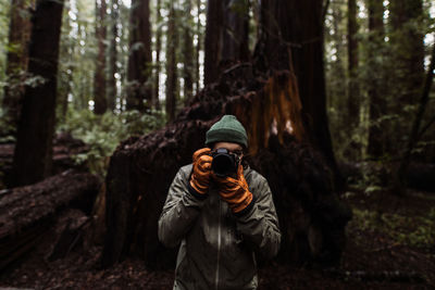 Full length of man photographing in forest