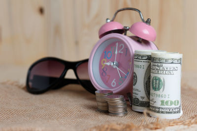 Close-up of alarm clock with sunglasses and money on burlap