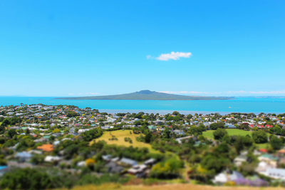 Scenic view of sea and green landscape against blue sky