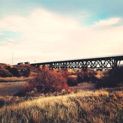 View of bridge over field against sky