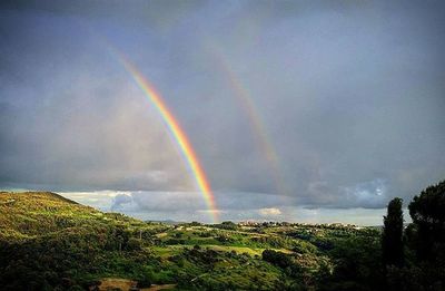 Rainbow over landscape against cloudy sky