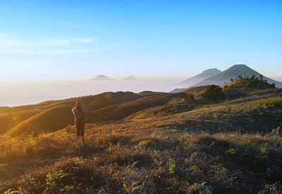 Woman walking on mountain against sky