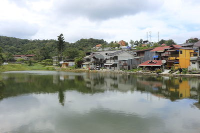 Houses by lake and buildings against sky