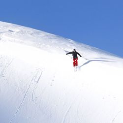 Man skiing on snowcapped mountain against clear sky