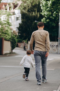 Rear view of men walking on street in city