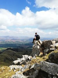 Man standing on rock against sky