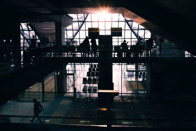 Silhouette people at railroad station platform in city against sky