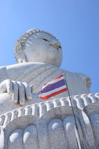 Low angle view of buddha statue and thai flag