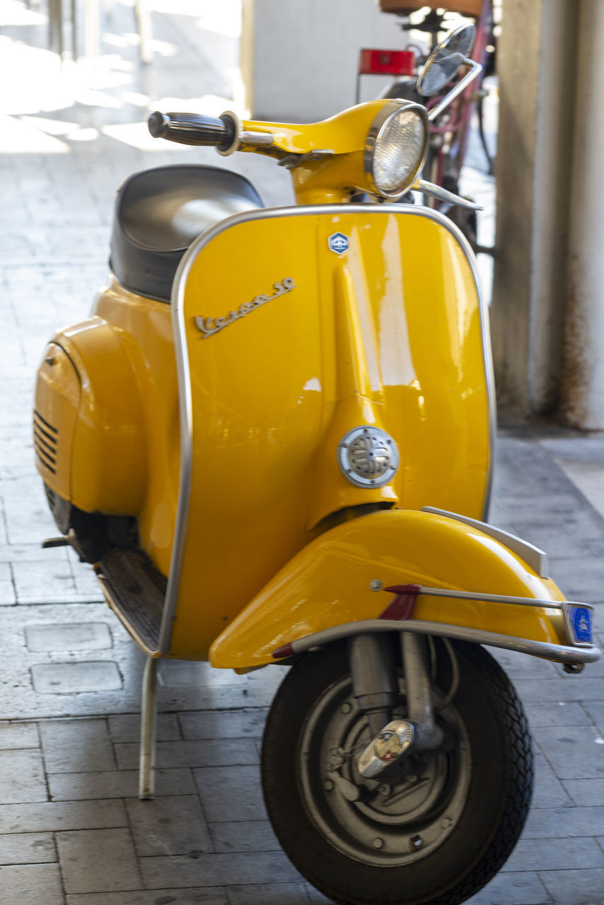 CLOSE-UP OF YELLOW MOTORCYCLE ON STREET