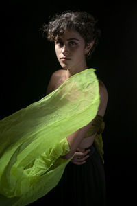 Portrait of smiling young woman standing against black background