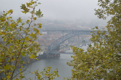 Arch bridge over river in city against sky