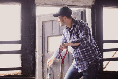 Farmer looking away while closing barn door