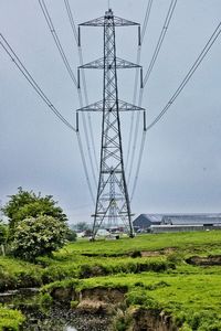 Electricity pylon on field against sky