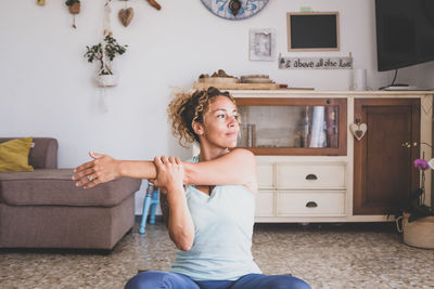 Smiling woman stretching while sitting at home