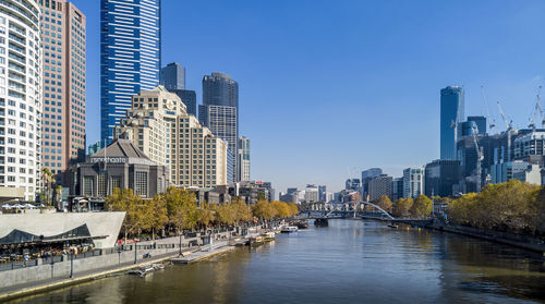 Modern buildings by river against sky in city