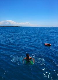 People swimming in sea against blue sky