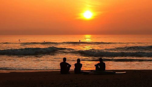 Silhouette of people on beach at sunset