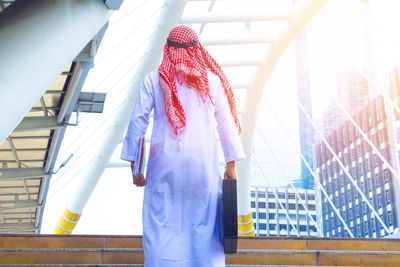 Rear view of woman standing by building