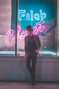 Full length of man standing against illuminated sign