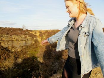 Smiling woman standing on field against sky