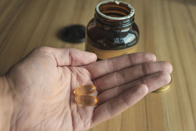 Yellow transparent omega 3 capsules in hand. taking medications. nutritional supplements