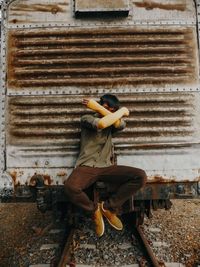 Man sitting on old train and covering face with arms