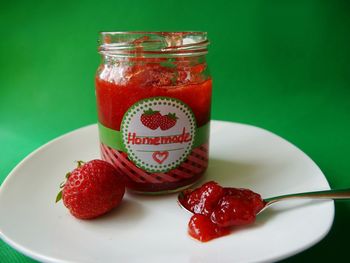 Close-up of homemade strawberry jam in glass on plate 