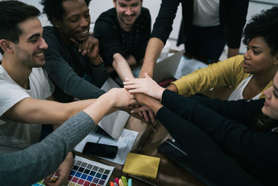 High angle view of colleagues stacking hands in meeting