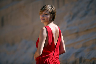 Portrait of young woman standing against rock formations