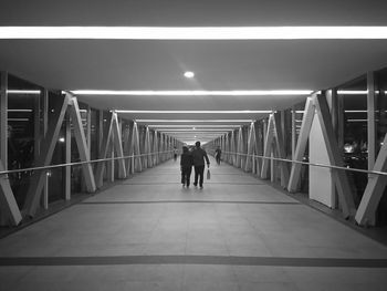 Rear view of couple walking on footbridge at night