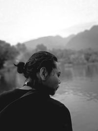 Portrait of woman looking at lake against mountain