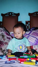 Portrait of cute boy sitting on bed at home