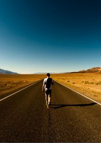 Rear view of man walking on road