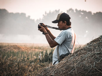 Side view of man holding camera on field