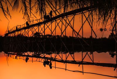 Silhouette bridge over lake against sky during sunset