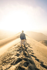 Rear view of man walking on sand