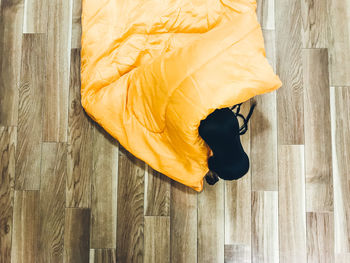 Directly above shot of miniature pinscher with yellow fabric on hardwood floor