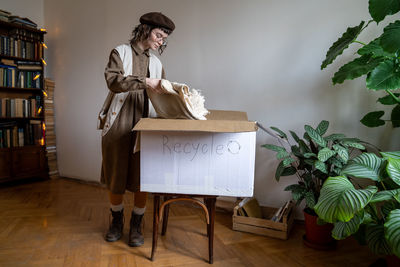 Eco-friendly teen girl packing old organic cotton clothes in cardboard box for recycling, reuse