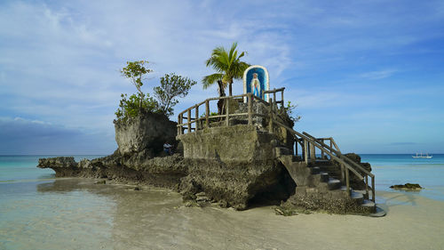 Virgin mary statue on built structure at beach against sky