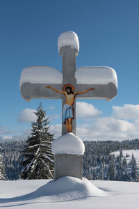 Cross on field against sky during winter