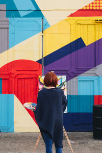 Rear view of woman standing against multi colored building