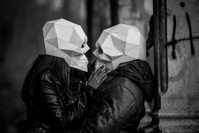 Side view of man and woman wearing skull masks