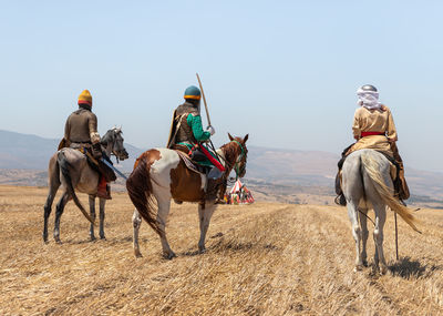 View of people riding horses on beach